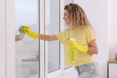 Camları paçavra ve deterjanla temizleyen kadın.