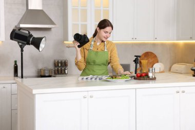 Mutfaktaki masada yemekle kompozisyon oluşturan kadın. Profesyonel yemek fotoğrafçılığı.