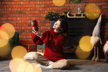 Evde şöminenin yanında Noel hediyesi olan genç bir kadın. Bokeh etkisi