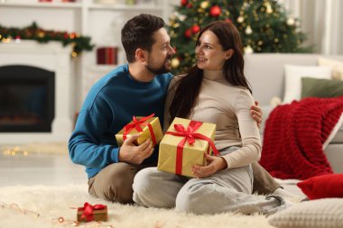 Kutuları olan mutlu çift Noel için dekore edilmiş odada birlikte vakit geçiriyor.