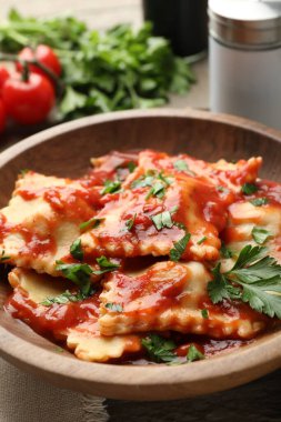 Domates soslu lezzetli ravioli ve ahşap masada maydanoz, yakın plan.