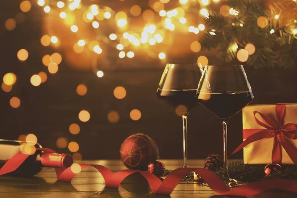 Noel topları, şarap, hediye kutusu ve bokeh ışıkları olan bir kart tasarımı.