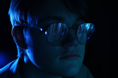 Siyah arka planda yansıması olan gözlüklü bir adam, yakın plan.