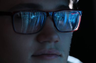 Siyah arka planda yansıması olan gözlüklü bir adam, yakın plan.