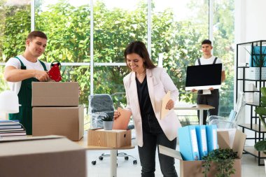 Taşınma günü. Ofisteki kutulara farklı eşyalar koyan bir grup işçi.