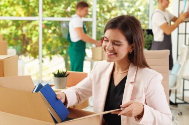 Taşınma günü. Ofisteki kutulara farklı eşyalar koyan bir grup işçi.