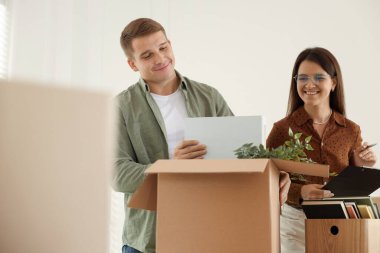 Taşınma günü. İşçiler ofisteki karton kutulara farklı eşyalar koyuyorlar.