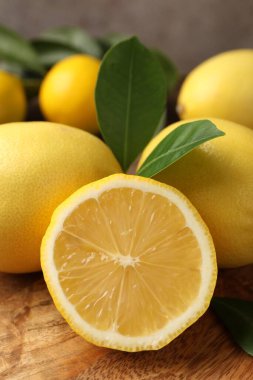 Ahşap masa üzerinde yeşil yapraklı limonların tamamı gri arka planda, yakın plan