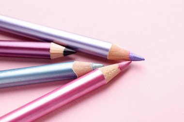 Pembe arka planda parlak göz kalemleri, yakın plan. Metin için boşluk