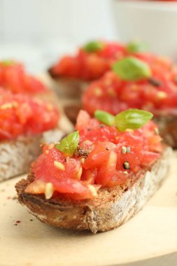 Domatesli lezzetli bruschettalar ve ahşap tahtada fesleğen, yakın plan.