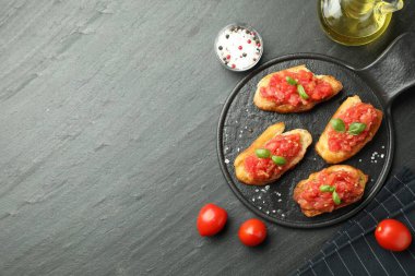 Siyah masada servis edilen domatesli ve fesleğenli lezzetli bruschettalar. Metin için boşluk