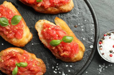 Siyah masada servis edilen domatesli ve fesleğenli lezzetli bruschetalar.