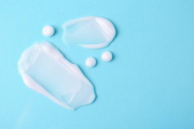 Açık mavi arka planda nemlendirici krem örnekleri. Metin için boşluk