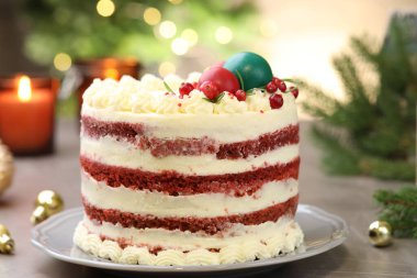 Noel dekorlu lezzetli sünger kek ve gri desenli masa üzümlü üzümlü, bulanık ışıklara karşı, yakın plan. Bokeh etkisi