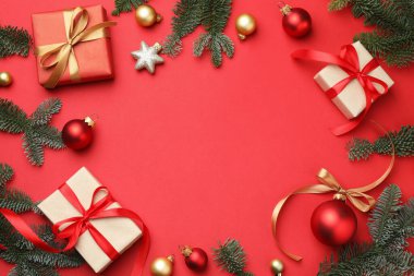 Köknar ağacı dalları, hediyeler ve kırmızı arka planda Noel dekoru, düz bir zemin. Metin için boşluk