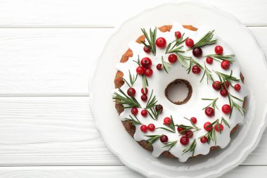 Beyaz ahşap masa üzerinde kremalı, kızılcıklı ve biberiyeli lezzetli bir Noel pastası. Metin için boşluk