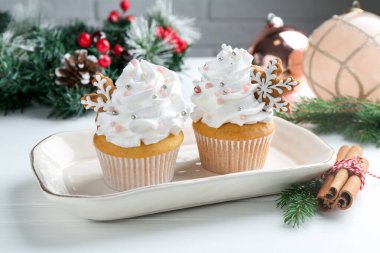 Noel dekorlu lezzetli kekler ve beyaz ahşap masa üzerinde tarçın, yakın plan.