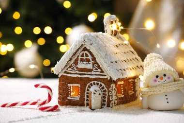 Zencefilli kurabiye evi, kardan adam ve baston şekerler Noel ışıklarına karşı, yakın plan. Bokeh etkisi