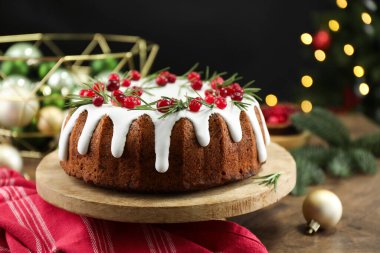 Üzerinde krema, kızılcık ve biberiye olan nefis bir Noel pastası. Siyah arka planda, bulanık ışıklarla, yakın plan. Bokeh etkisi