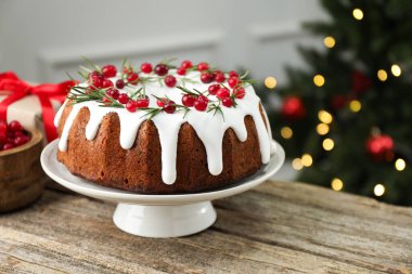 İçerideki ahşap masada kremalı, kızılcıklı ve biberiyeli nefis Noel pastası, yakın plan. Bokeh etkisi