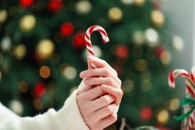 Noel ağacına karşı baston şekerli kadın, yakın plan. Bokeh etkisi