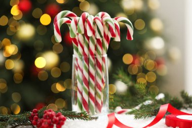 Yapay kar üzerinde cam çubuk şekerlemeler bulanık Noel ışıklarına karşı. Bokeh etkisi