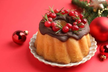 Kırmızı arka planda yaban mersinli lezzetli pasta ve Noel dekoru, yakın plan.