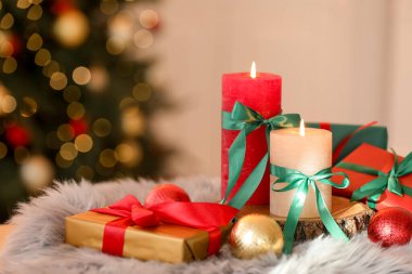 Bulanık ışıklara karşı sahte kürkte mum yakmak ve Noel süsü vermek. Bokeh etkisi