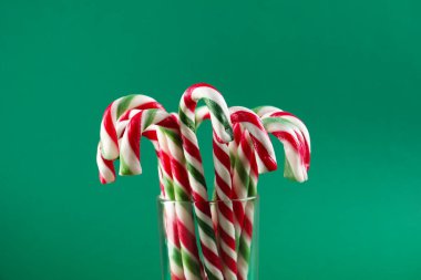 Yeşil arka planda cam çubuk şekerler, yakın plan. Noel hediyesi