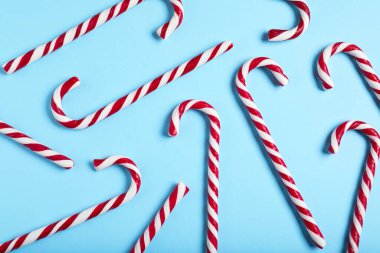 Açık mavi arka planda bir sürü şeker kamışı var. Noel hediyesi