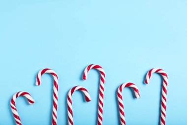 Açık mavi arkaplanda bir sürü baston şeker, metin için yeri olan düz bir yer. Noel hediyesi