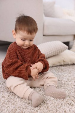 Evde yerde oturan şirin bir bebek.