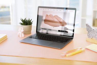 Ofisteki ahşap masada dizüstü bilgisayarı, dekoru ve pembe paspası olan şık bir iş yeri.