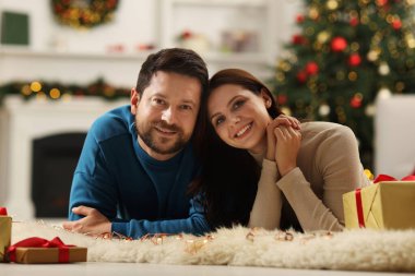 Mutlu çift Noel için dekore edilmiş odada birlikte vakit geçiriyor.