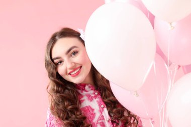 Pembe arka planda balonları olan güzel bir kadın.