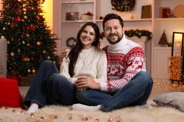 Mutlu çift Noel için dekore edilmiş odada birlikte vakit geçiriyor.