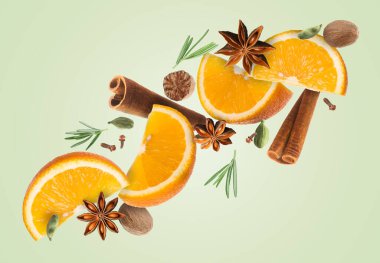 Sıcak şarap malzemeleri: soluk yeşil zemine düşen portakal dilimleri ve baharatlar. Geleneksel Noel içkisi