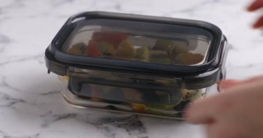 Beyaz mermer masada lezzetli meyve salatasıyla cam kap açan kadın, yakın plan. Sağlıklı çerez