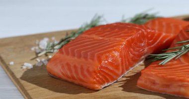 Somon fileto parçaları, biberiye, masaya tuz ve limon, yakın plan. Kamera sağa hareket ediyor