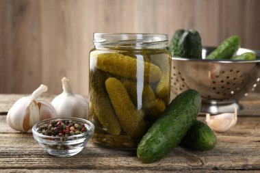 Kavanozda turşular, ahşap masada taze salatalık ve baharatlar, yakın plan.