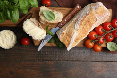 Tereyağlı, fesleğenli, domatesli ekmek dilimleri ve tahta masa üzerinde bıçak. Metin için boşluk