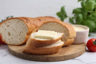 Beyaz mermer masada tereyağlı, fesleğenli ve domatesli baget kes.