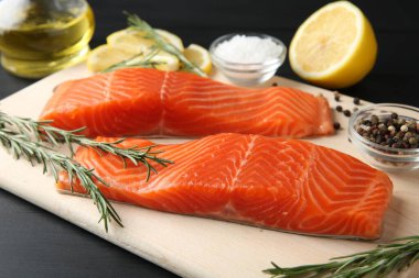 Somon filetosu, baharat ve limon parçaları siyah ahşap masada, yakın plan.