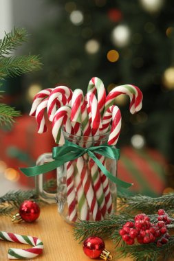 Duvarcı kavanozunda bir sürü şeker kamışı ve ahşap masada bulanık ışıklara karşı Noel dekoru. Bokeh etkisi