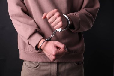 Siyah arka planda kelepçeli adam, yakın plan.