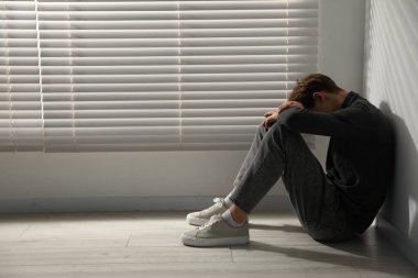 Depresyondaki genç çocuk pencerenin yanında, mesaj için yer var.