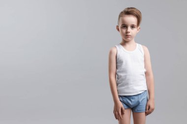 Açık gri arka planda iç çamaşırlı küçük bir çocuk. Metin için boşluk