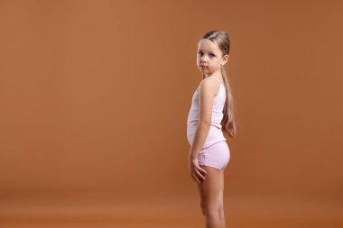 Kahverengi arka planda iç çamaşırlı küçük bir kız. Metin için boşluk