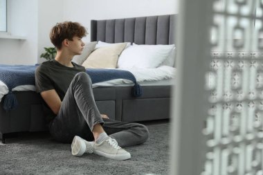 Evde yatağın yanında depresyonda olan genç bir çocuk.