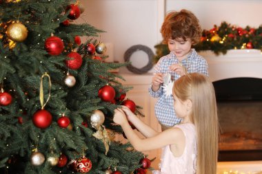 Evde Noel ağacı süsleyen sevimli çocuklar.